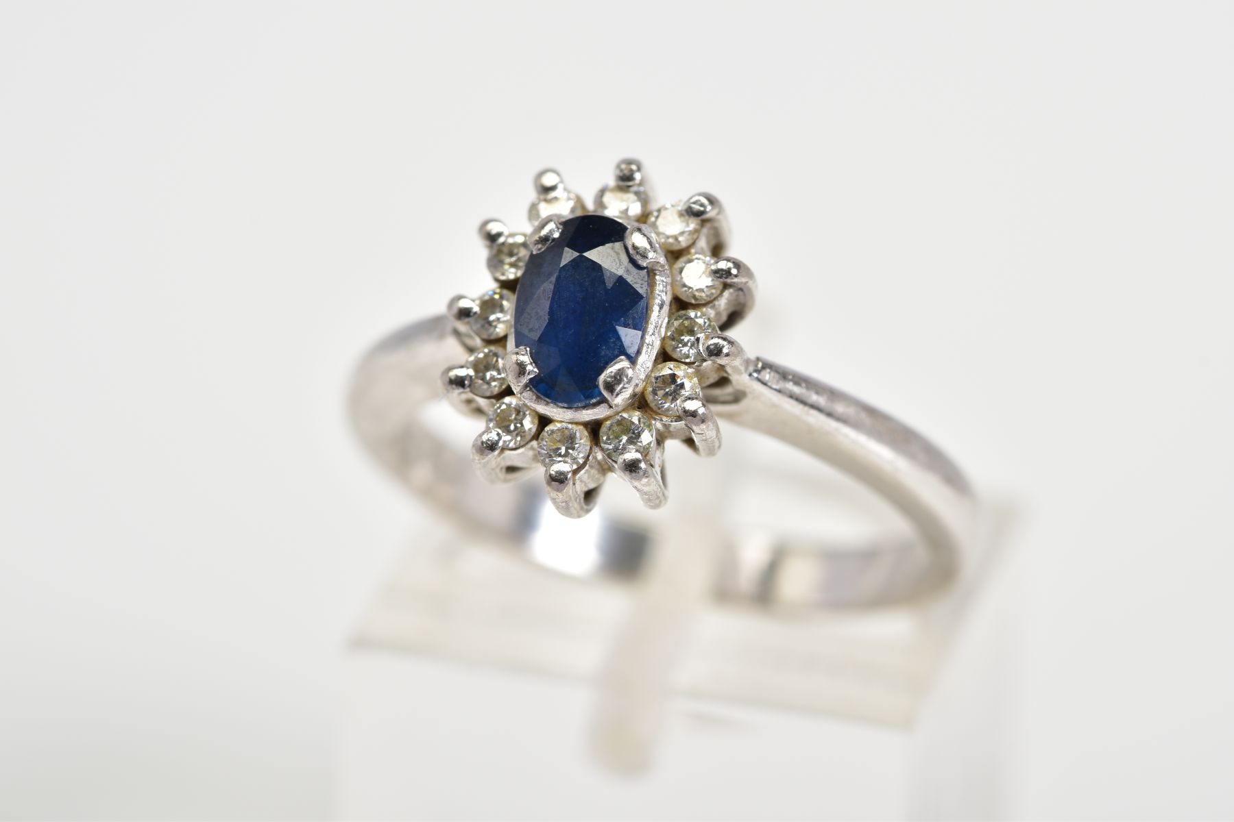 A SAPPHIRE AND DIAMOND OVAL CLUSTER RING, sapphire measuring approximately 6mm x 4mm, estimated