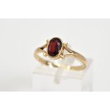 A 9CT GOLD GARNET RING, set with a central oval cut garnet to the bifurcated shoulders and plain