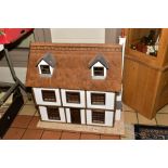 A WOODEN DOLLS HOUSE, modelled as a three storey thatched town house, front opens to reveal four