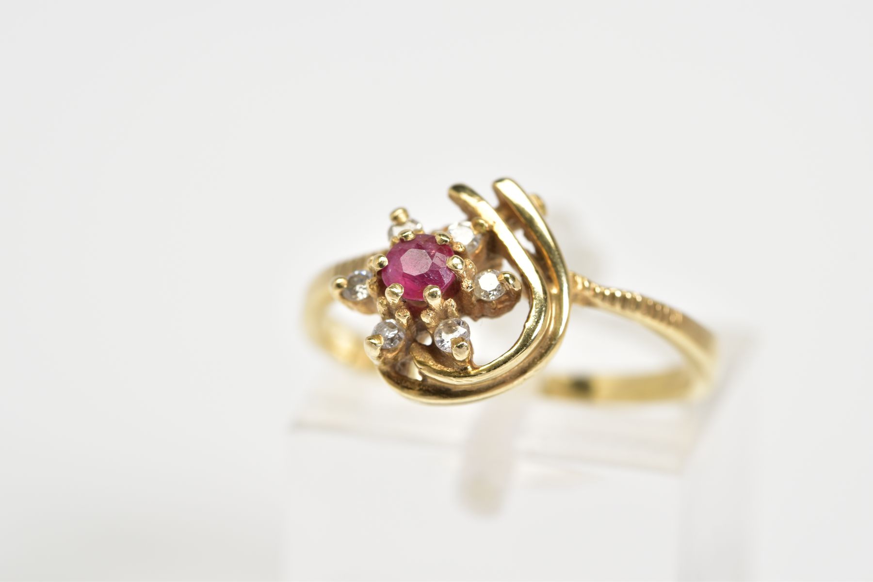 A 9CT GOLD CLUSTER RING, designed as a flower with a central circular cut ruby and brilliant cut