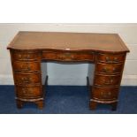 A REPRODUX MAHOGANY SERPENTINE FRONTED KNEE HOLE DESK with a brown tooled leather inlay top above