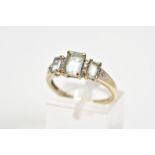 A THREE STONE RING, designed with three emerald cut assessed as aquamarine interspaced with single