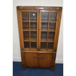 A 1940'S OAK GLAZED TWO DOOR BOOKCASE, above double cupboard doors, width 84cm x depth 28cm x height