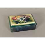 A MOORCROFT POTTERY RECTANGULAR COVERED BOX, 'Spring Flowers' pattern on green/blue ground,