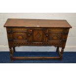 A REPRODUCTION OAK TWO DOOR SIDE CABINET, carved panel doors on turned legs united by front and side