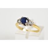 A THREE STONE RING, set with a central cushion cut sapphire flanked with two round brilliant cut