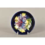 A SMALL MOORCROFT POTTERY FOOTED DISH, 'Hibiscus' pattern on blue ground, impressed marks and