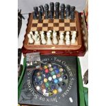 A BOXED SOLITAIRE GAME, having hand blown marble pieces with a wooden chess board and carved