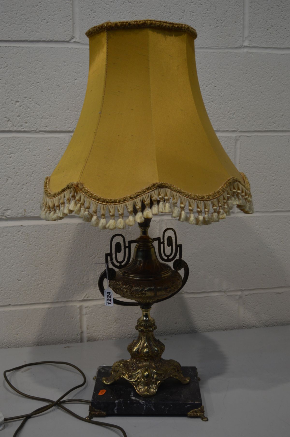 A BRASS EWER SHAPED TABLE LAMP on a slate base with a fabric shade (one loose foot)