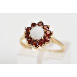 A 9CT GOLD CLUSTER RING, the tiered cluster set with a central opal with a circular cut garnet