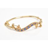 AN EARLY 20TH CENTURY GEM SET BANGLE, the hinged bangle designed with a curved panel set with a