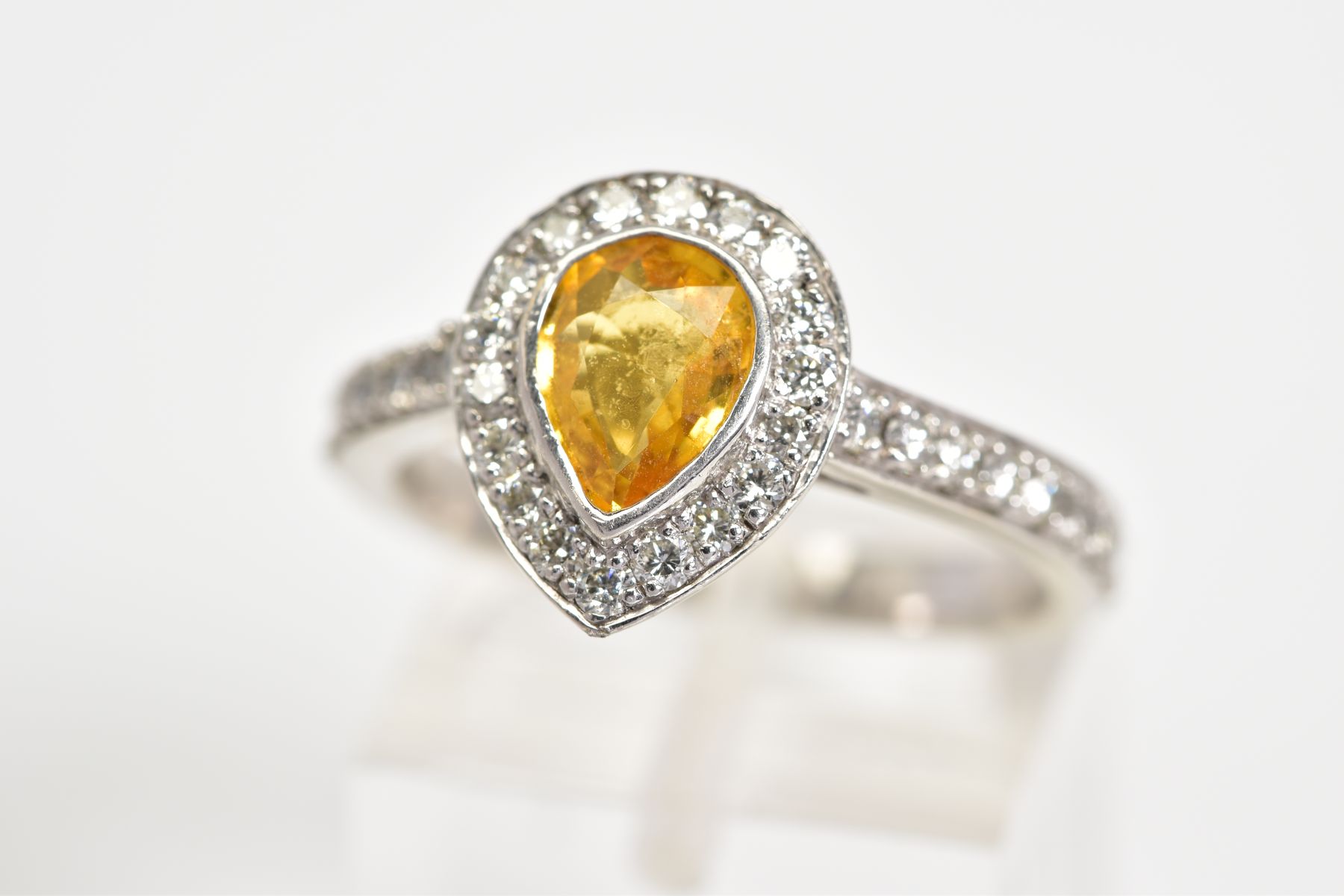 A YELLOW TOPAZ SET RING, the white metal ring set with a pear cut topaz with a round brilliant cut