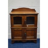 AN EARLY 20TH CENTURY OAK TWO TIER FOUR DOOR CABINET, the bottom section with two internal
