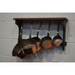 A SET OF FIVE GRADUATING COPPER PANS, with iron hooped handles on an oak hanging rack (6)