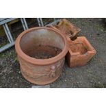 A CIRCULAR TERRACOTTA GARDEN URN, with cherub decoration to the sides, together with a pair of