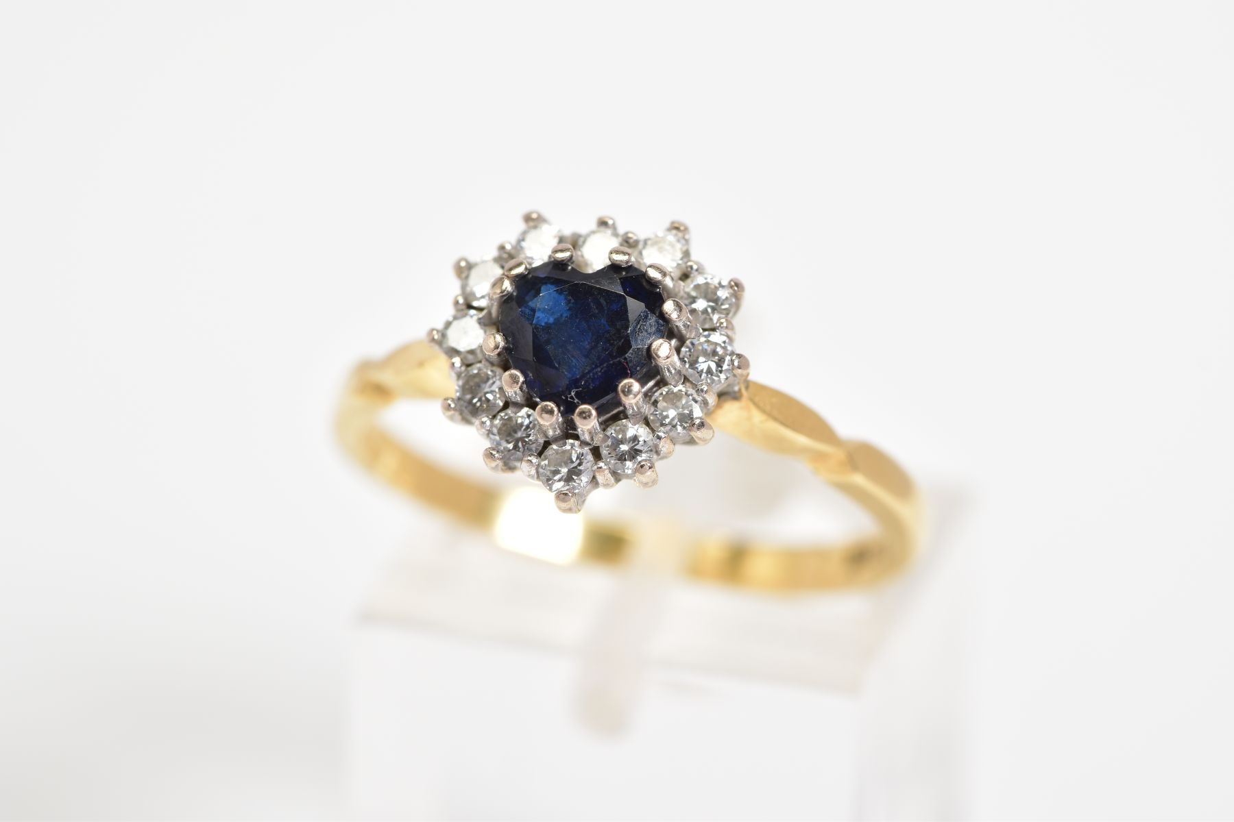 AN 18CT GOLD CLUSTER RING, set with a central heart shape sapphire with a round brilliant cut