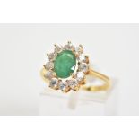 AN EMERALD CLUSTER RING, a yellow metal ring, set with a central oval cut emerald with a circular