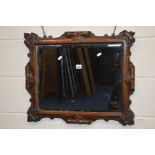AN EARLY 20TH CENTURY CARVED OAK BEVELLED EDGE WALL MIRROR, with foliate and scrollage decoration