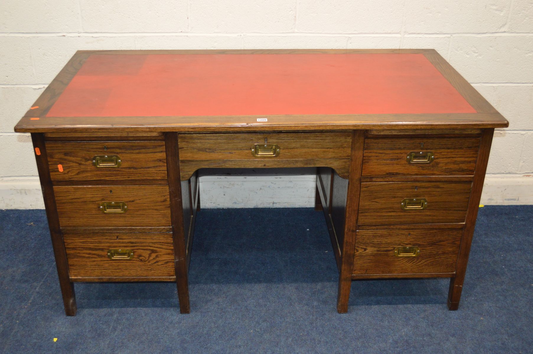 A MID 20TH CENTURY STAINED OAK KNEE HOLE DESK, with a red leather top and seven drawers with brass