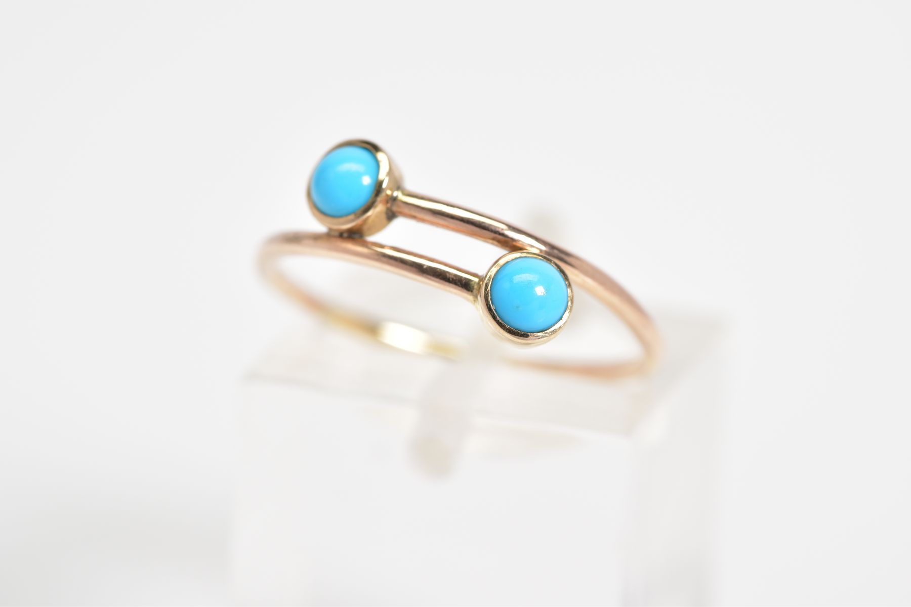 A TURQUOISE SET RING, of crossover design, set with two round cabochon turquoise, ring size L,