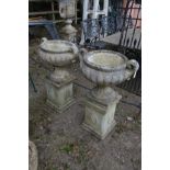 A PAIR OF COMPOSITE COMPAGNA GREEK GARDEN URNS, with twin handles on a separate square plinth,