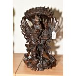 A CARVED ORIENTAL HARDWOOD SCULPTURE OF A MAN ASTRIDE A TWO HEADED BEAST WITH WINGS, standing on a
