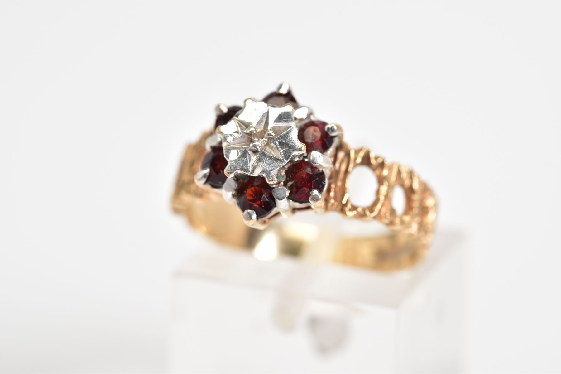 A 9CT GOLD CLUSTER RING, of tiered design set with a central single cut diamond, with a circular cut