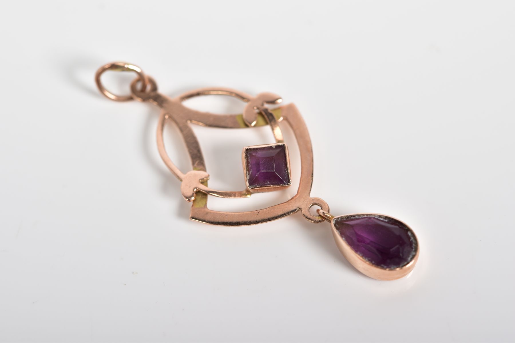 AN AMETHYST PENDANT, of openwork design set with a square cut amethyst suspending a further pear cut
