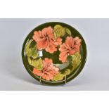 A MOORCROFT POTTERY SHALLOW BOWL, green ground with coral hibiscus, sounds dull when tapped, painted