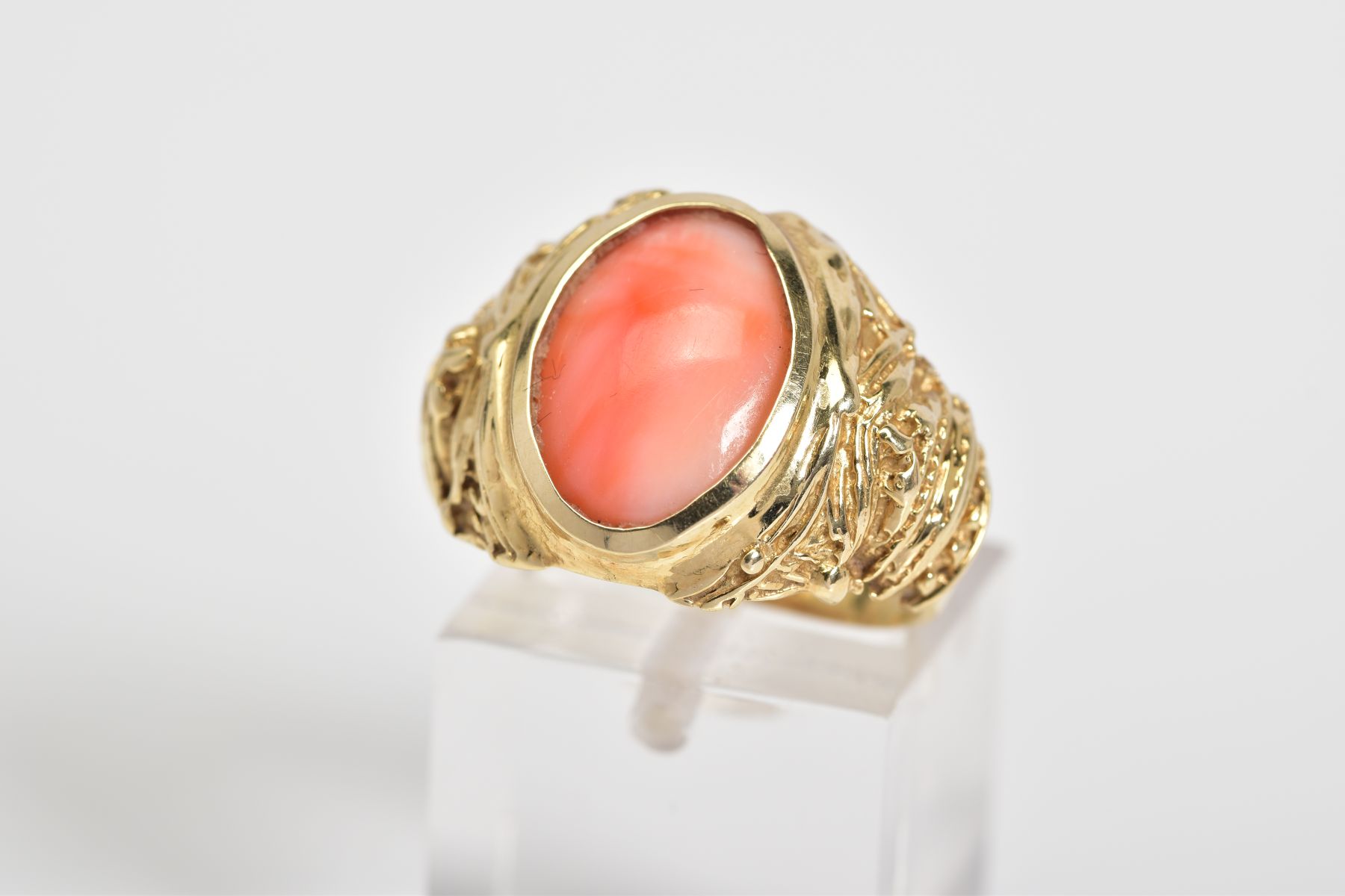 A CORAL SET RING, the yellow metal ring designed with a central oval coral panel within a collet