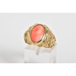 A CORAL SET RING, the yellow metal ring designed with a central oval coral panel within a collet