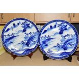 A PAIR OF LATE 19TH CENTURY JAPANESE BLUE AND WHITE CHARGERS, painted with landscapes within a