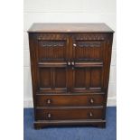 A REPRODUCTION OAK LINENFOLD TWO DOOR CABINET, with two drawers, width 86cm x depth 47cm x height