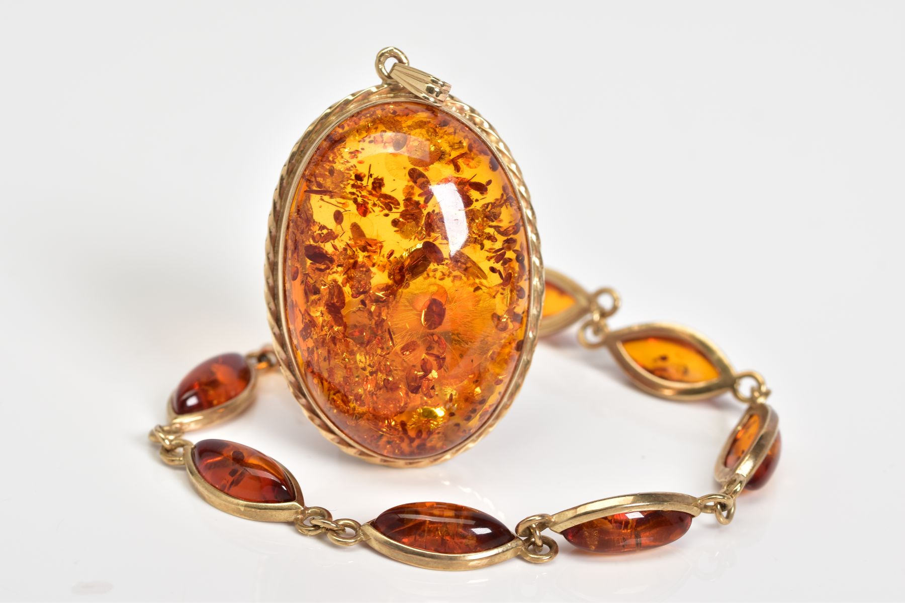 A 9CT GOLD AMBER BRACELET AND PENDANT, the bracelet designed with eight lozenge shape amber links,