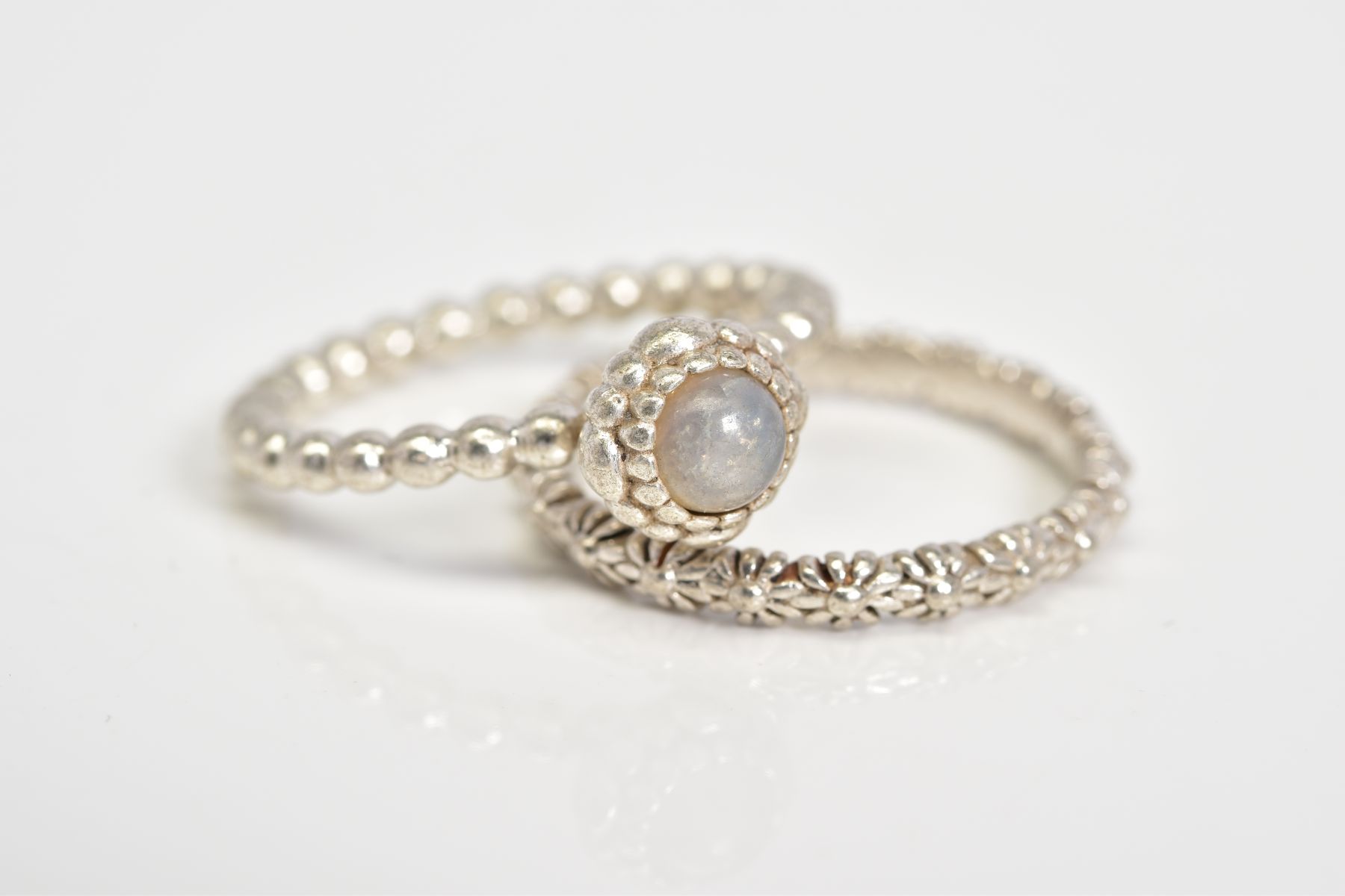 TWO WHITE METAL RINGS, the first a flower design band, stamped 925, ring size O, together with a