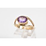 AN AMETHYST SET RING, yellow metal ring set with an oval cut amethyst within a collect mount to