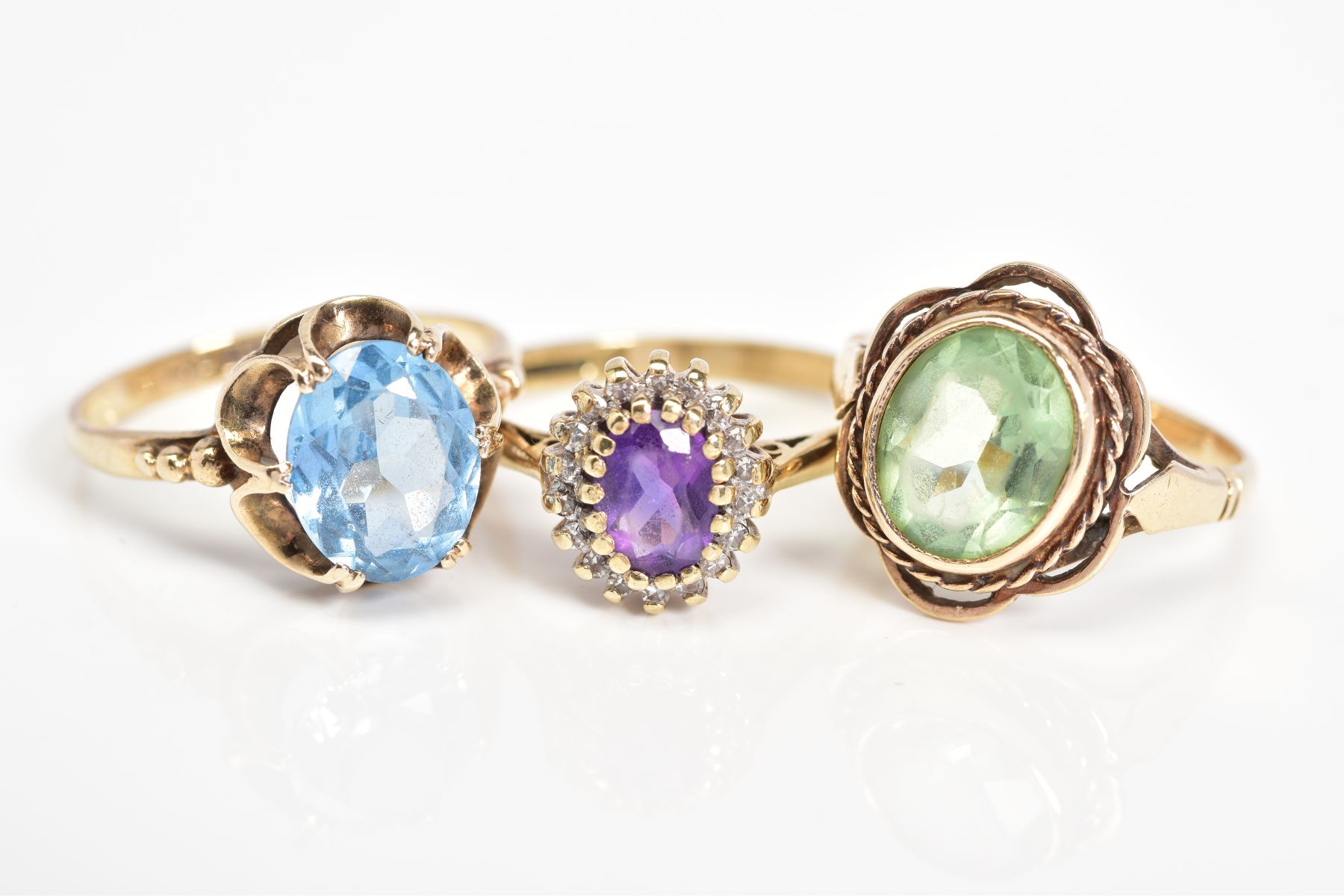 THREE 9CT GOLD GEM SET RINGS, to include an oval cut topaz within a scallop surround, with a 9ct