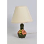 A MOORCROFT POTTERY TABLE LAMP, of bulbous form, green ground with coral hibiscus, cream fabric