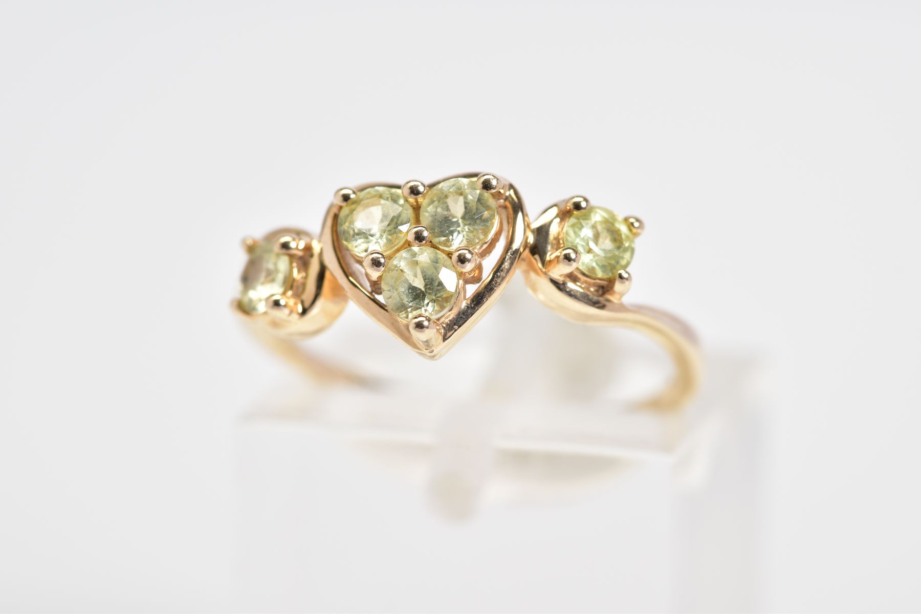 A 9CT GOLD RING, designed with a central heart panel set with three circular cut stones assessed