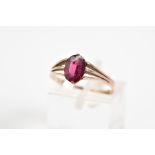 A 9CT GOLD GARNET RING, set with an oval cut garnet to the trifurcated shoulders and plain