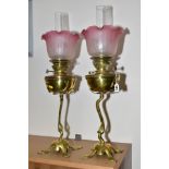 A PAIR OF ART NOUVEAU BRASS OIL LAMPS, clear glass chimneys (not a pair) with reproduction frilled