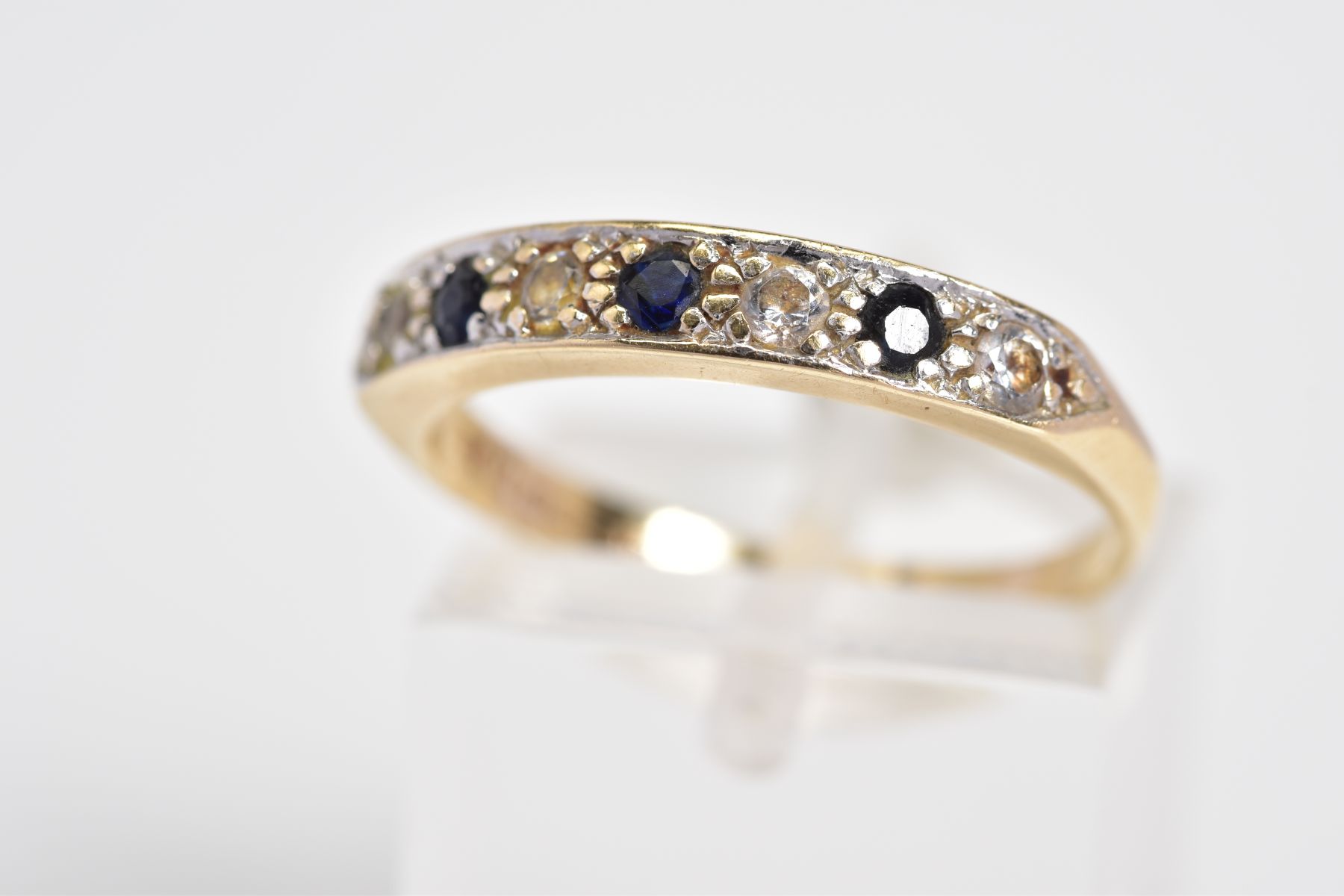 A 9CT GOLD HALF ETERNITY RING, set with three circular cut sapphires interspaced with four