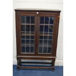 AN EARLY TO MID 20TH CENTURY OAK LEAD GLAZED TWO DOOR BOOKCASE, on barley twist front legs, width