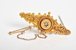 AN EARLY 20TH CENTURY 15CT GOLD BROOCH, the embossed floral panel with a raised circular centre