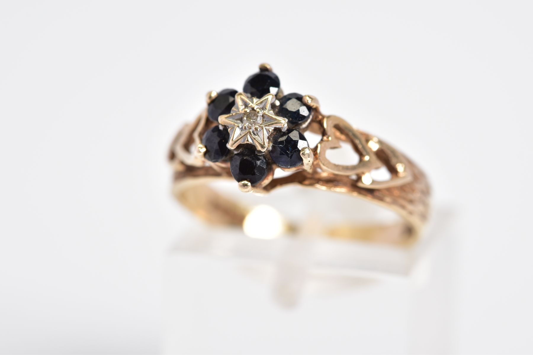 A 9CT GOLD SAPPHIRE AND DIAMOND CLUSTER RING, the cluster set with a single cut diamond within a