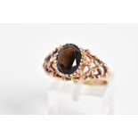 A 9CT GOLD SMOKEY QUARTZ RING, designed with a claw set oval cut smokey quartz and open work