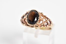 A 9CT GOLD SMOKEY QUARTZ RING, designed with a claw set oval cut smokey quartz and open work