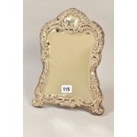 AN EDWARDIAN SILVER MOUNTED EASEL BACKED MIRROR, repousse foliate decoration, bevel edged mirror,
