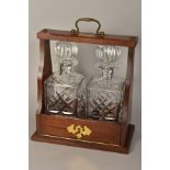 A TANTALUS, containing two cut glass decanters, with 'Total Service' plaque and carry handle,