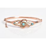 A 9CT ROSE GOLD EDWARDIAN BANGLE, the hinged bangle with an openwork scroll design front, central